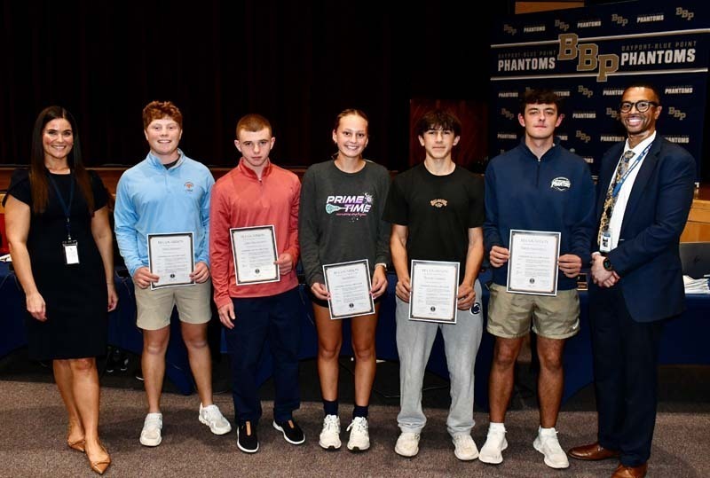Students holding certificates, smiling with board members.