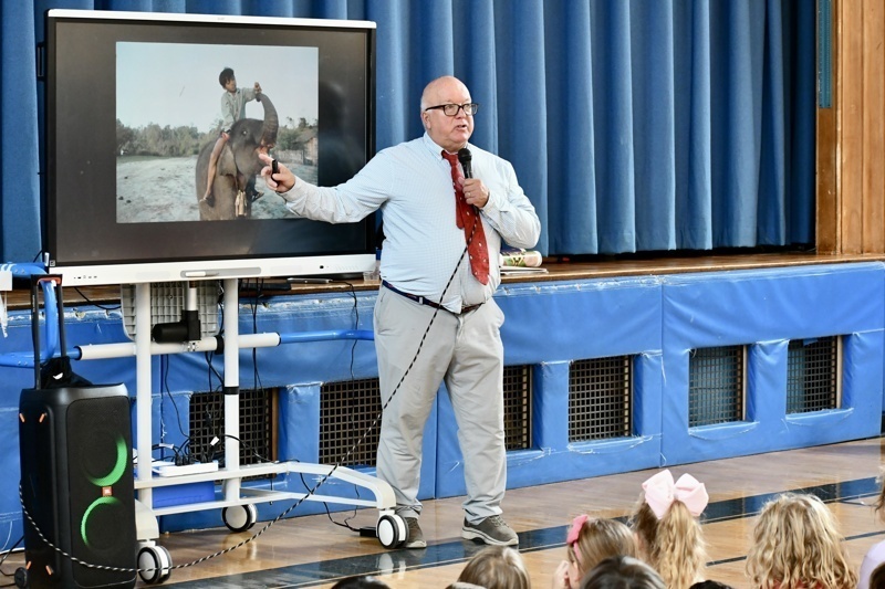 A person presents a slideshow to an audience using a screen and a microphone.
