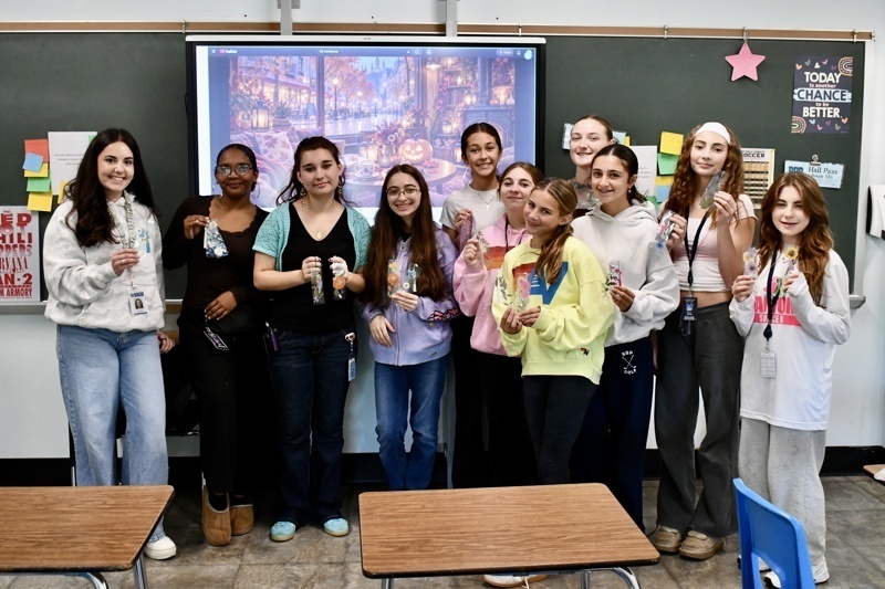 A group holds treats in front of a presentation screen in a classroom setting.