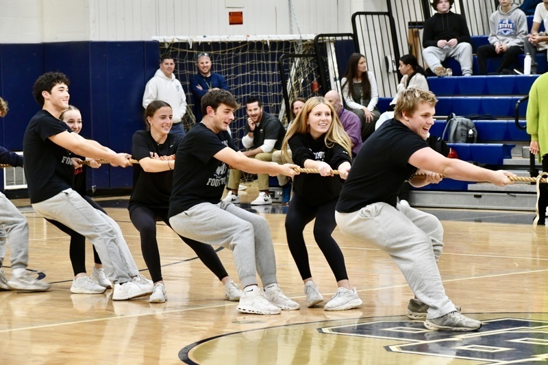 A group competes in a tug-of-war on a gymnasium floor during an event.
