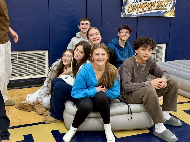 A group of people sits together on an inflatable couch in a gymnasium.