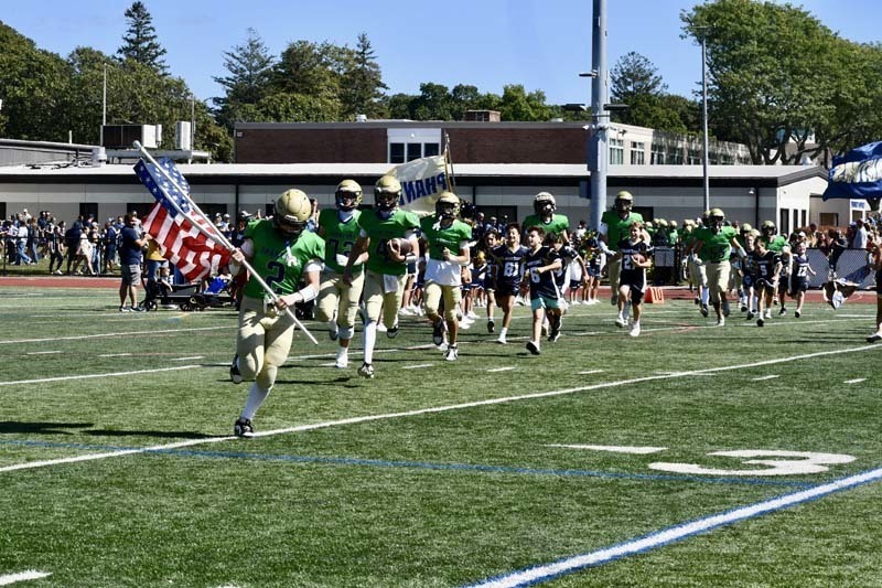 Football team running with American flag.