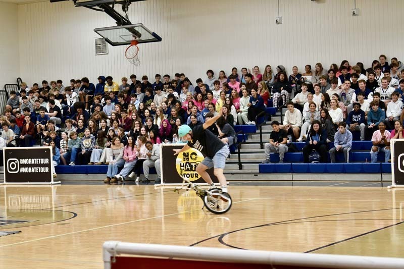 BMX professional doing tricks in gymnasium.