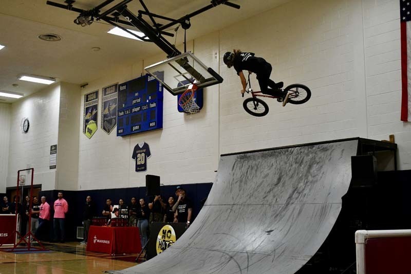 BMX professional doing tricks in gymnasium.