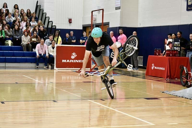 BMX professional doing tricks in gymnasium.