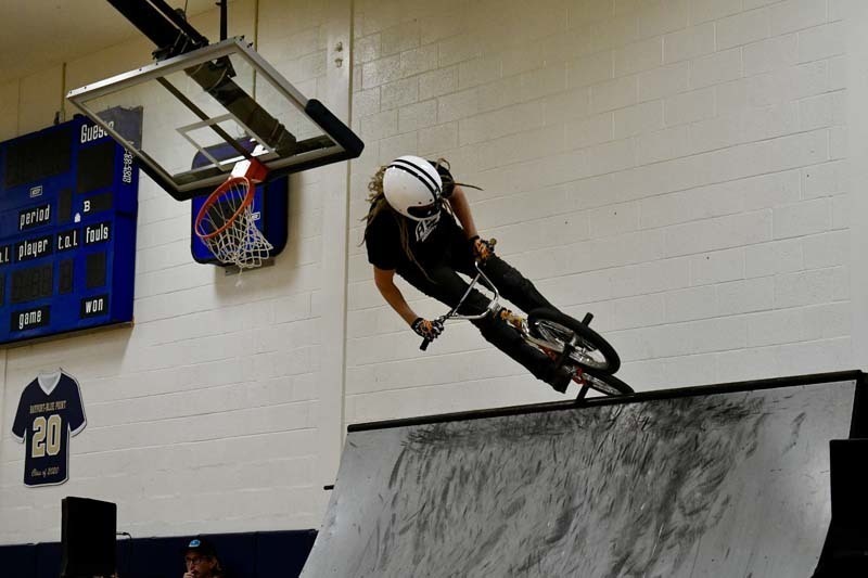 BMX professional doing tricks in gymnasium.