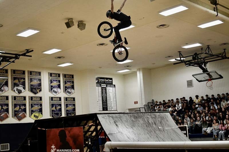 BMX professional doing tricks in gymnasium.