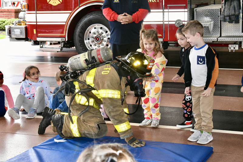 students with firefighter by fire truck