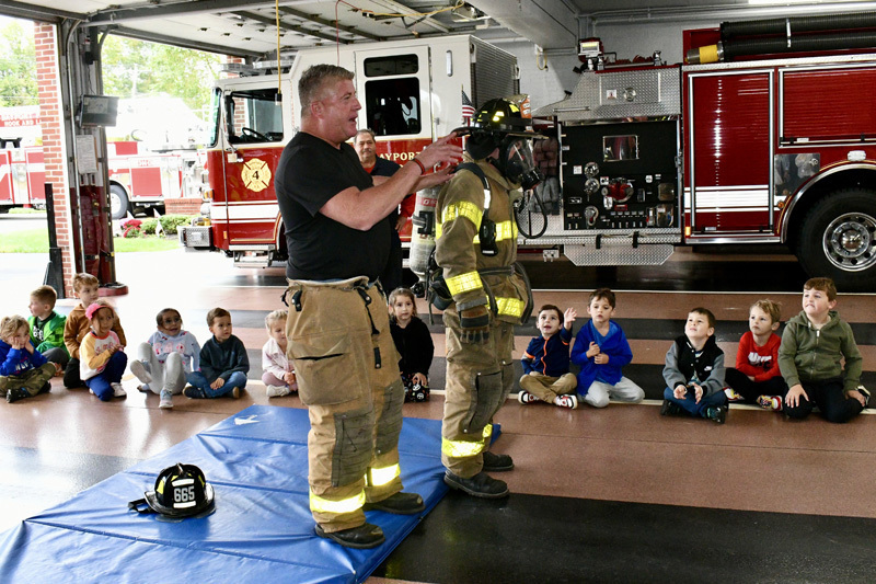 students with firefighter by fire truck