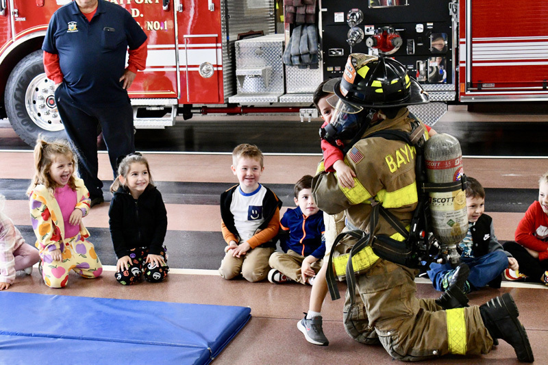 students with firefighter by fire truck
