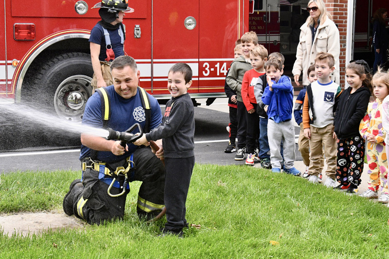 students with firefighter by fire truck