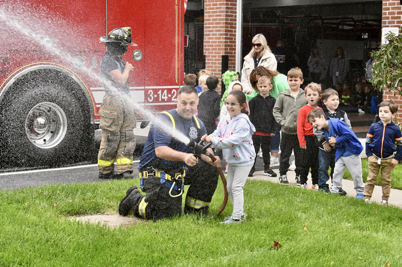 students with firefighter by fire truck