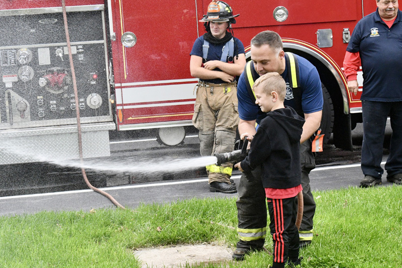 students with firefighter by fire truck
