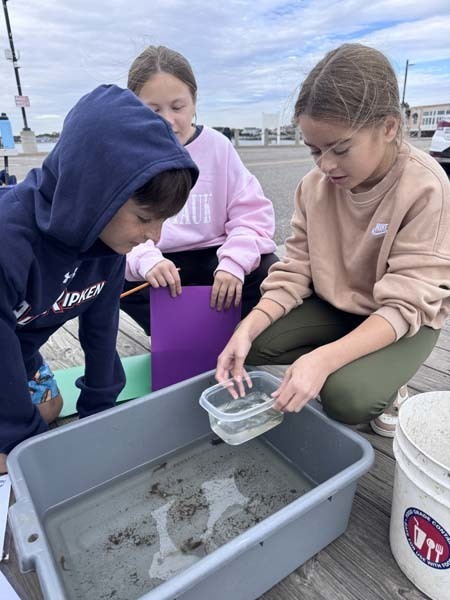 Students outside looking through box.