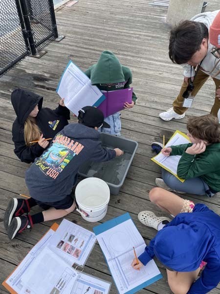 Students outside looking through box.