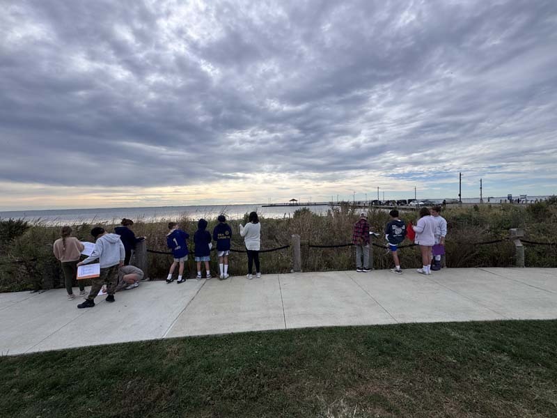 Students outside looking through box.