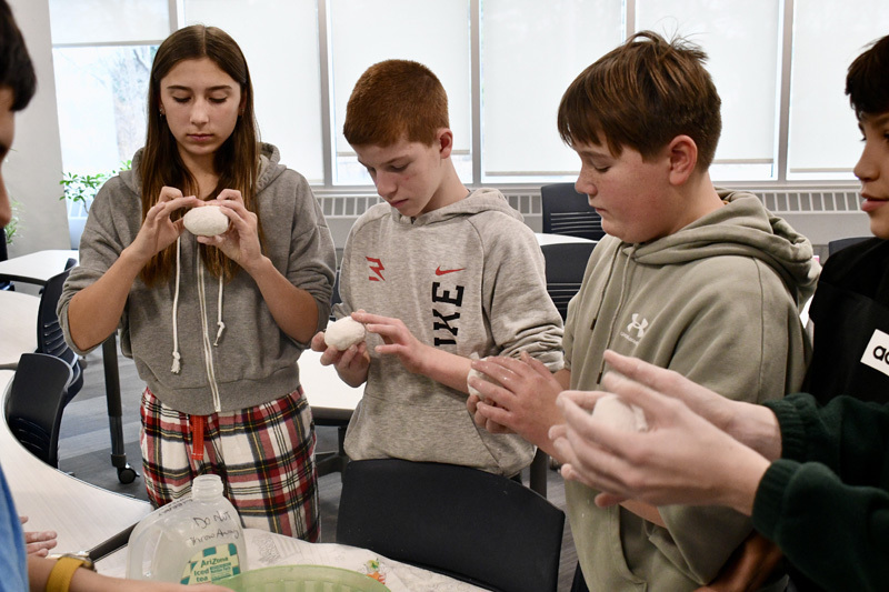 A group of children gathered around a table, focused on a science project