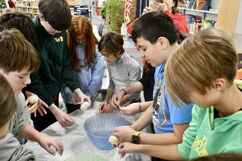 A group of children gathered around a table, focused on a science project