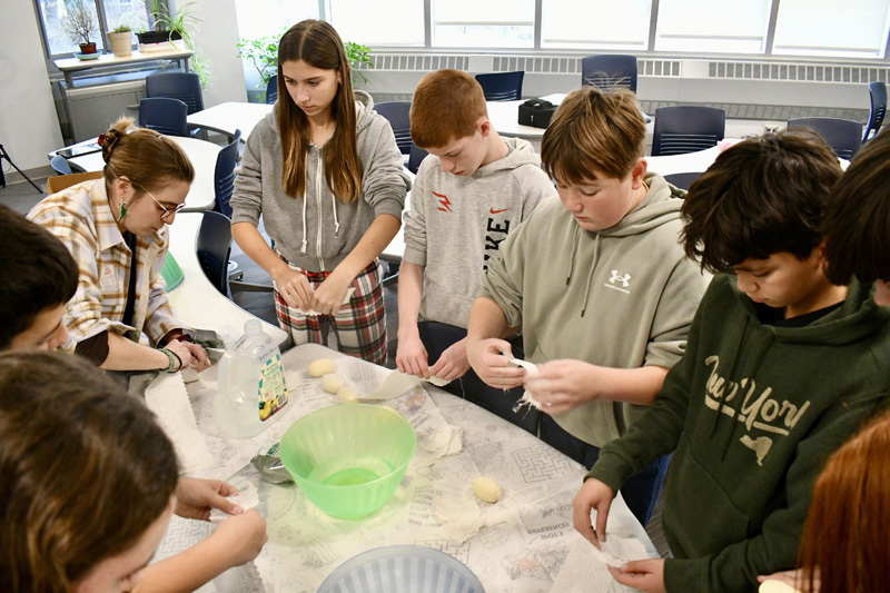 A group of children gathered around a table, focused on a science project