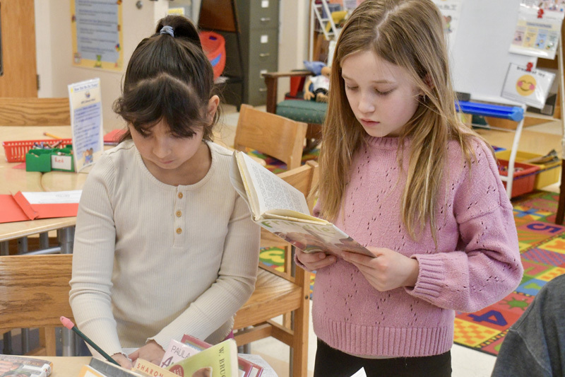  young children smiling at a classroom table, engaged in a playful activity.