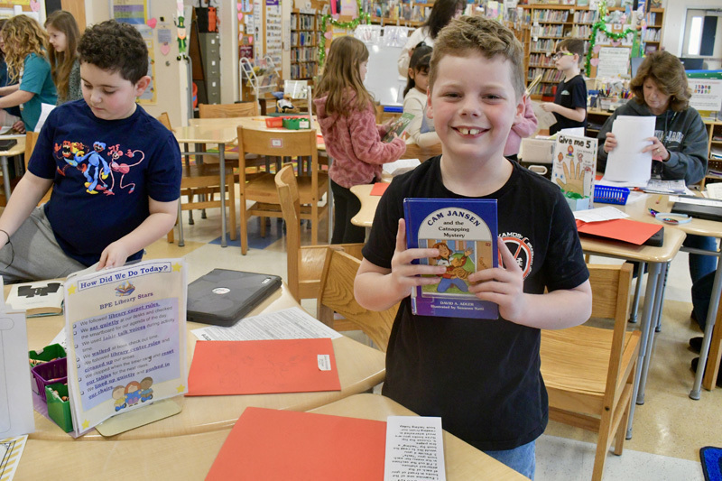  young children smiling at a classroom table, engaged in a playful activity.