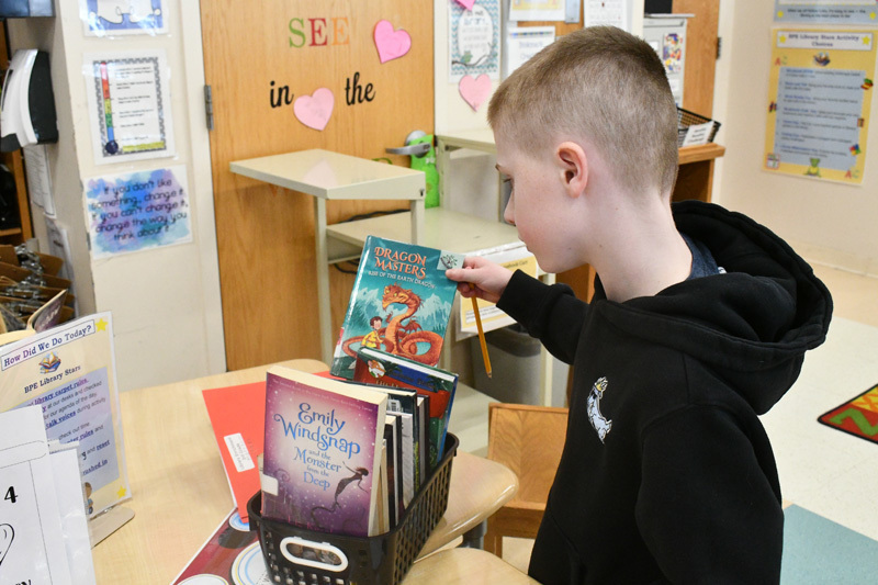  young children smiling at a classroom table, engaged in a playful activity.