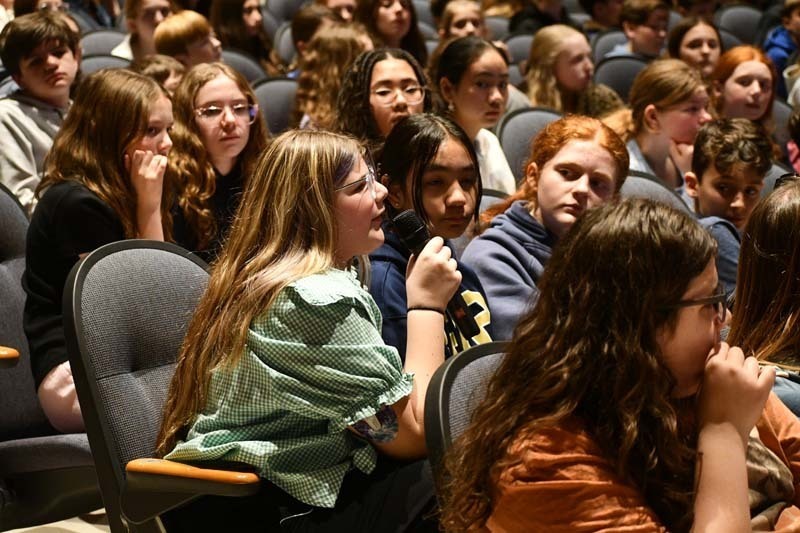 Students listening to speaker in auditorium.