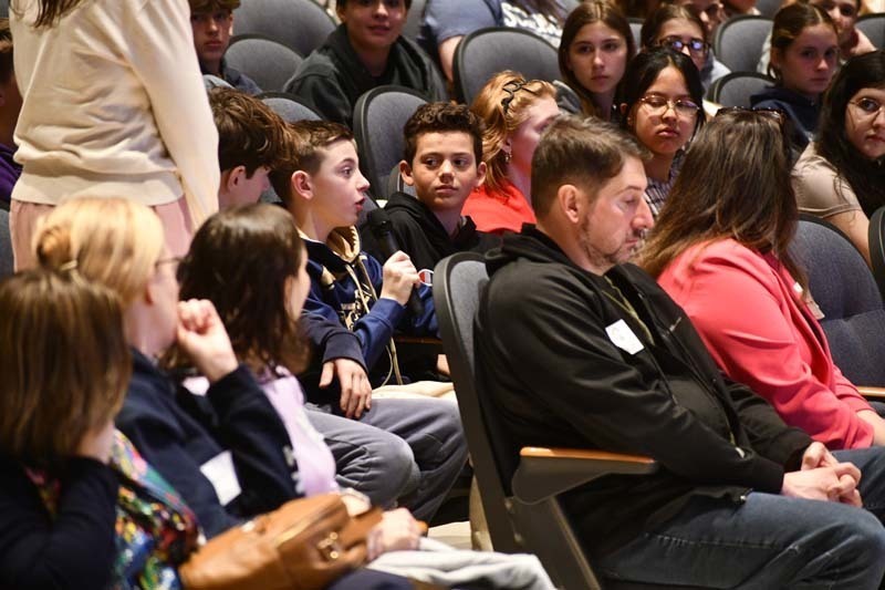 Students listening to speaker in auditorium.