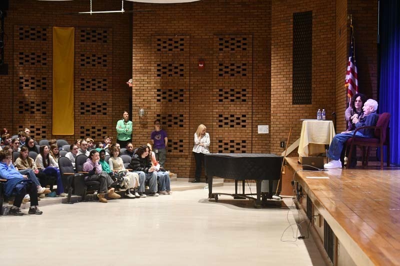Students listening to speaker in auditorium.