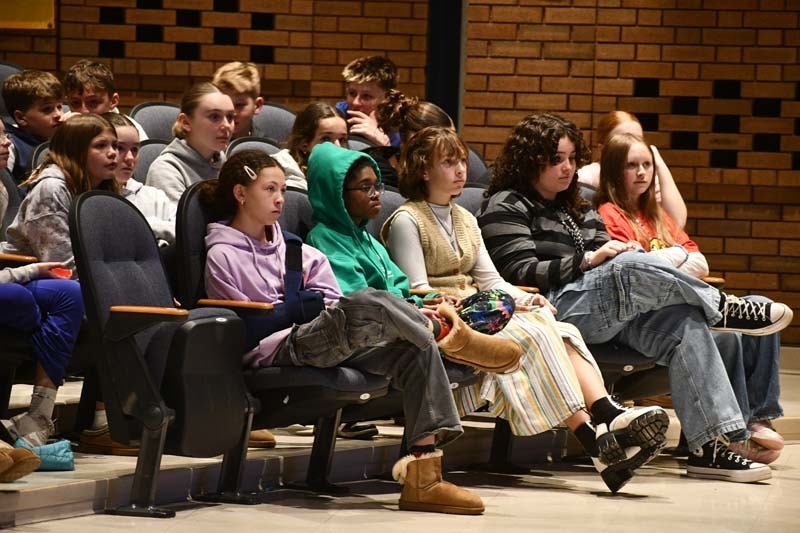 Students listening to speaker in auditorium.