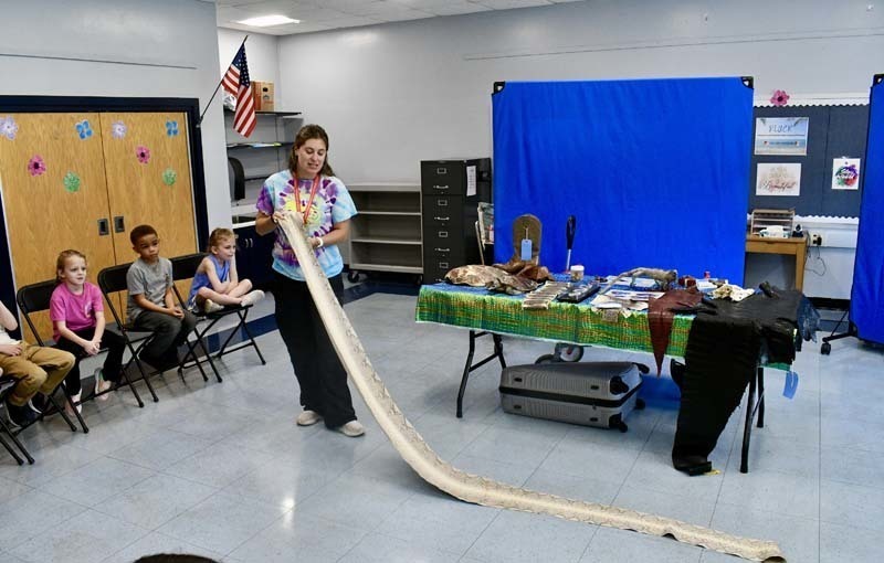Students looking at snake being held by instructor.