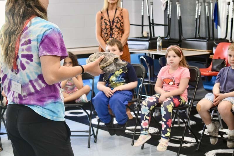 Students looking at snake being held by instructor.