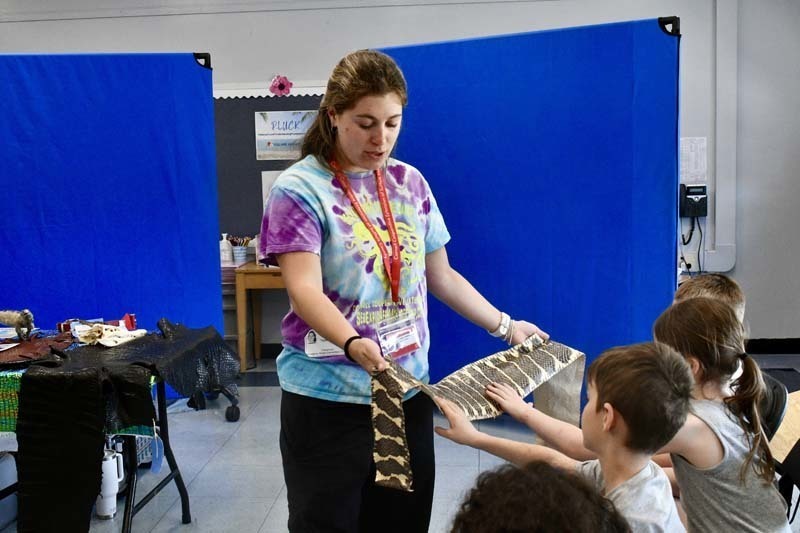 Students looking at snake being held by instructor.