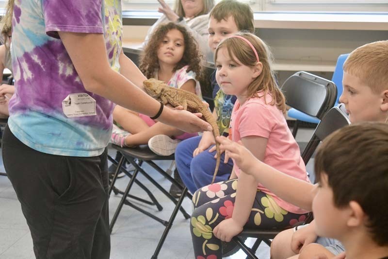 Students looking at snake being held by instructor.