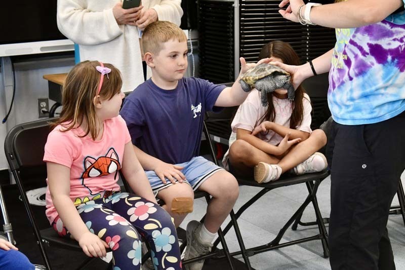 Students looking at snake being held by instructor.