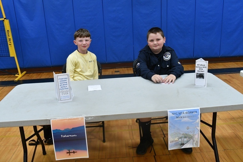 Young students engaged in a classroom activity, interacting at tables with props and costumes, fostering creativity and learning in a vibrant gymnasium setting.