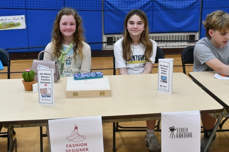Young students engaged in a classroom activity, interacting at tables with props and costumes, fostering creativity and learning in a vibrant gymnasium setting.