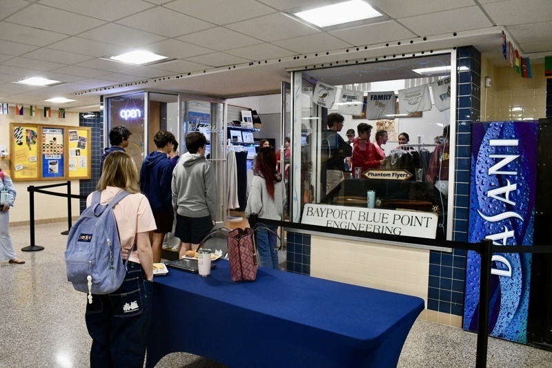 Interior view of Long Island Sign Designs showcasing a variety of custom apparel, including hoodies and printed designs, along with promotional pricing.
