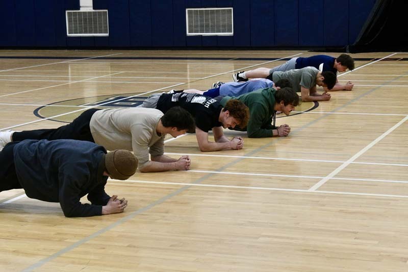 Students doing planks in gymnasium.