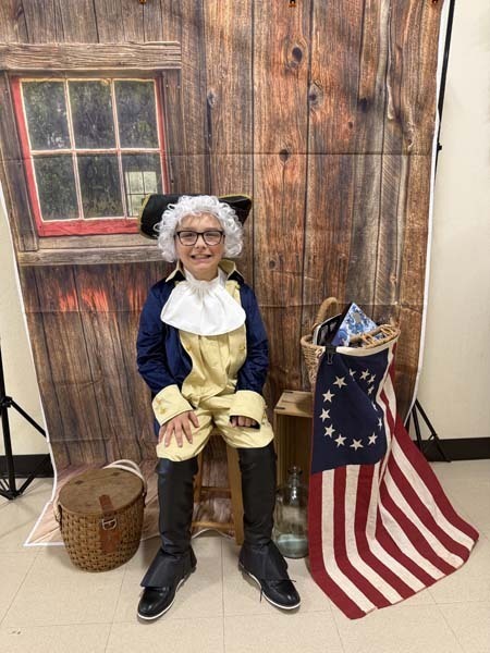 Students smiling, dressed in 1700s costumes.