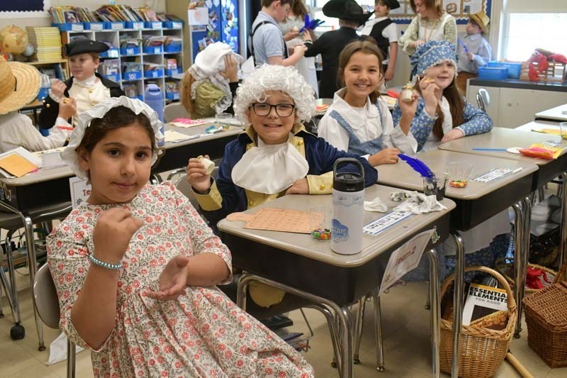 Students smiling, dressed in 1700s costumes.