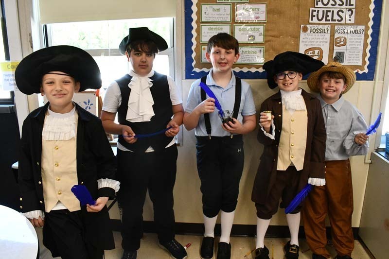 Students smiling, dressed in 1700s costumes.