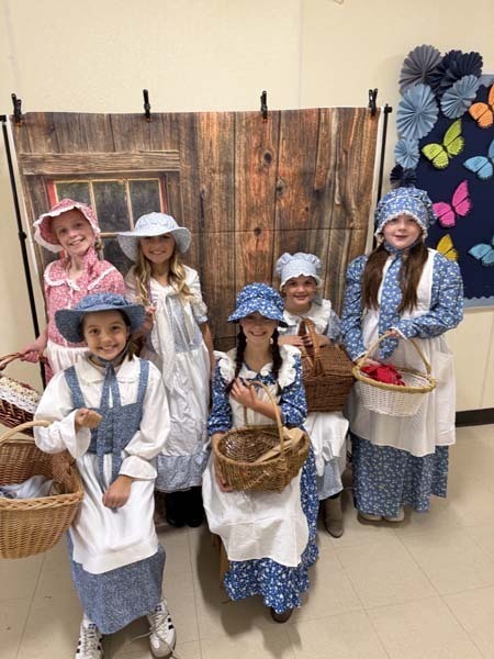 Students smiling, dressed in 1700s costumes.