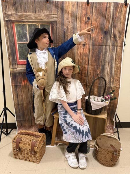 Students smiling, dressed in 1700s costumes.