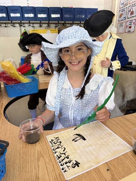 Students smiling, dressed in 1700s costumes.