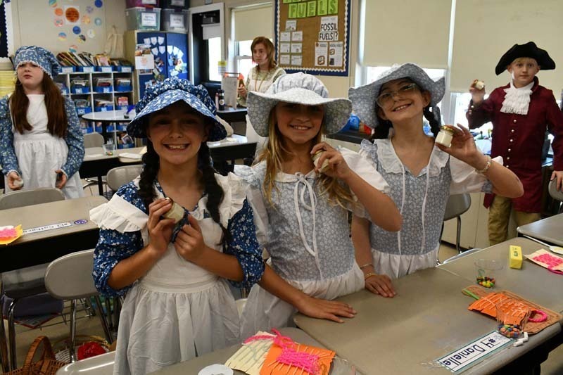 Students smiling, dressed in 1700s costumes.
