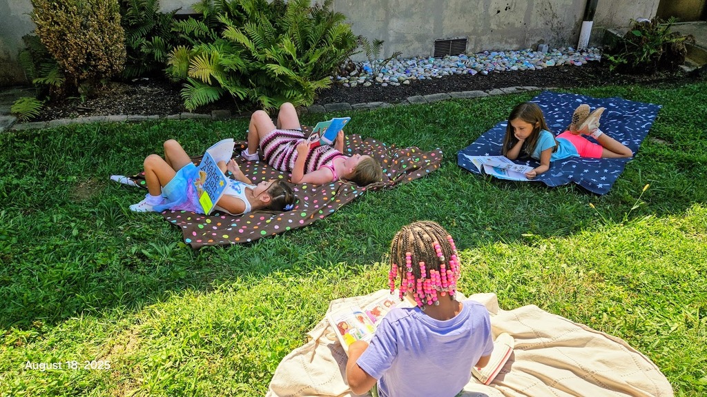 Students laying in the grass reading on a nice sunny day at Parkwood Elementary 