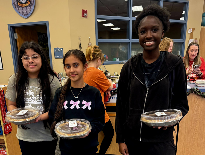 Three students posing with the pies they won.