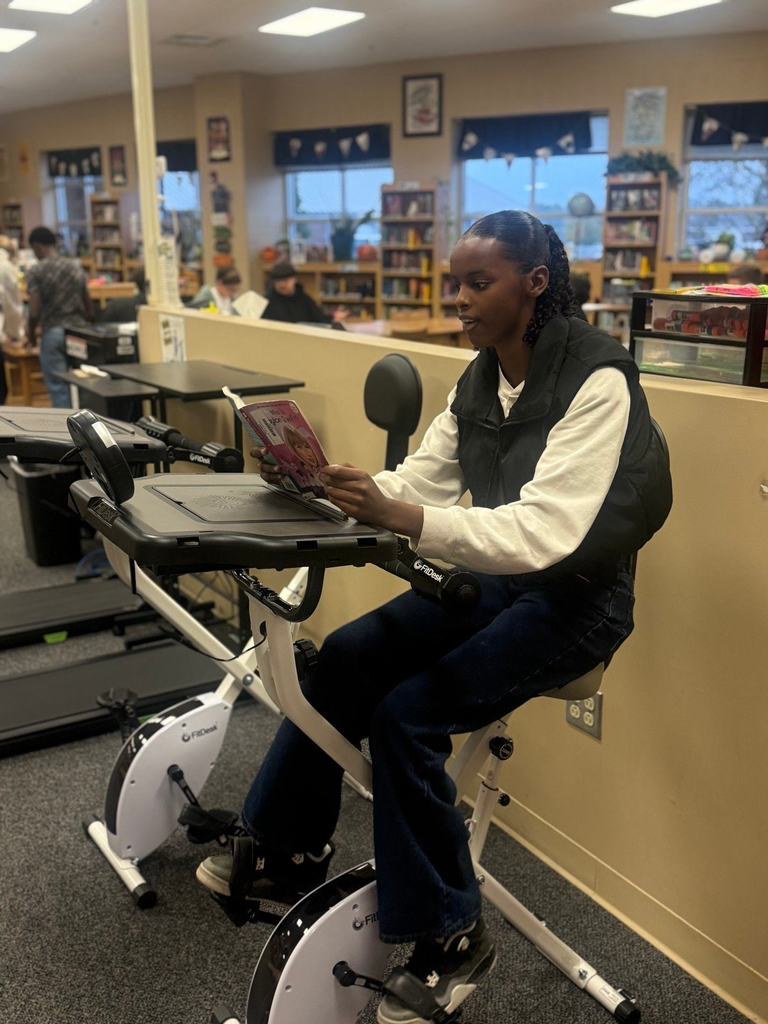 Student reading while working out in the library on reading bikes