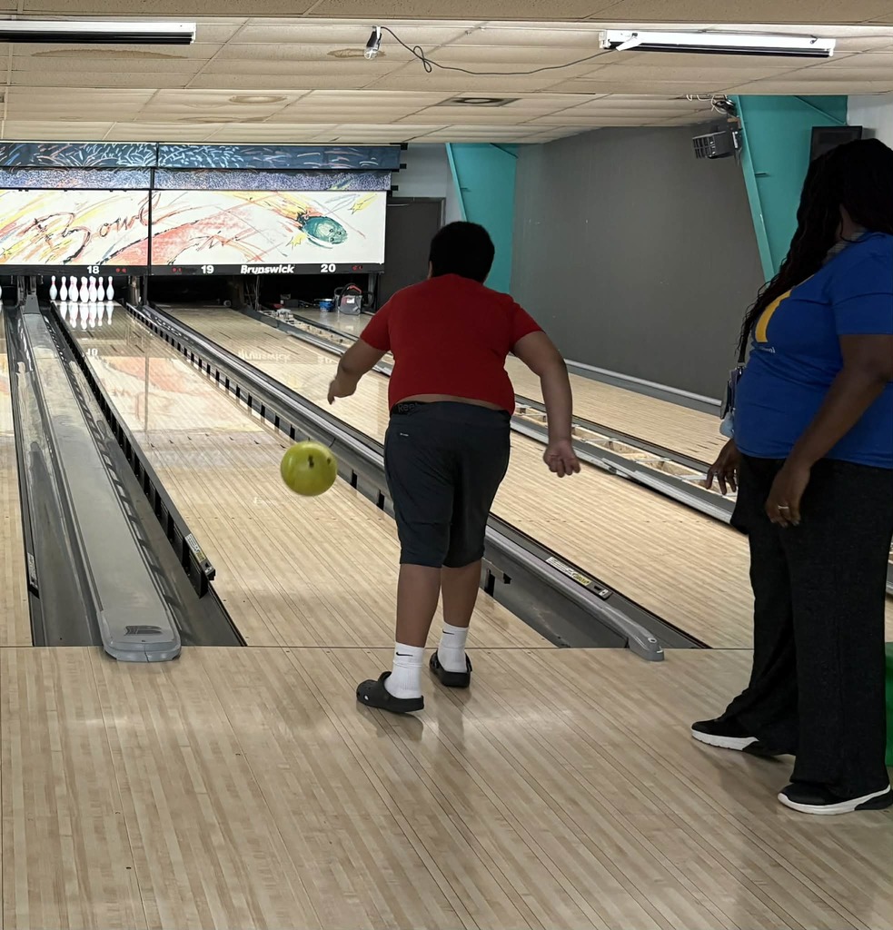 Student bowling as a teacher watches